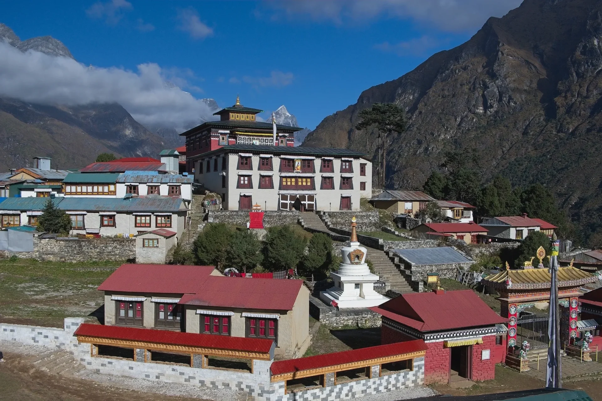 Group of skiers posing on a snowy mountain with lake and peaks behind.
