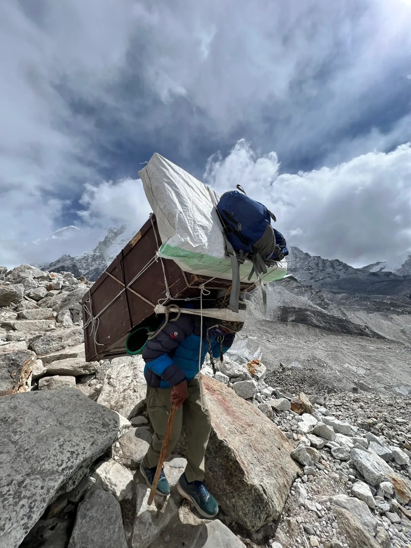 Group of skiers posing on a snowy mountain with lake and peaks behind.