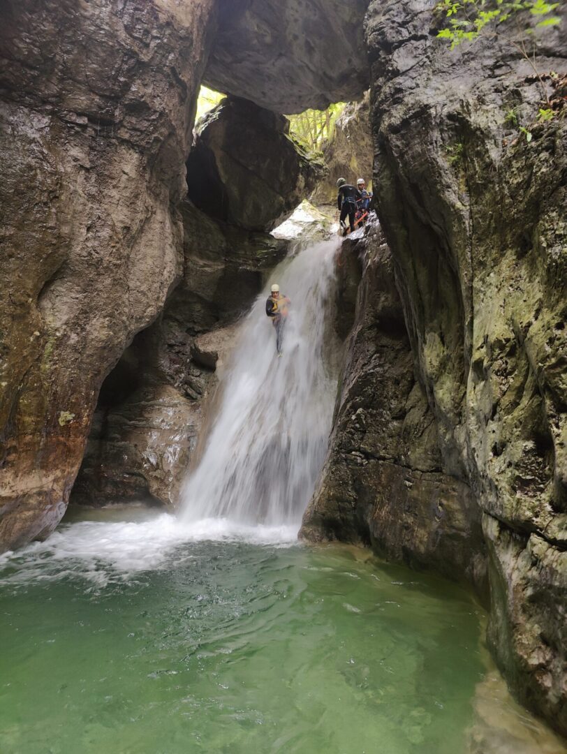 Group of skiers posing on a snowy mountain with lake and peaks behind.