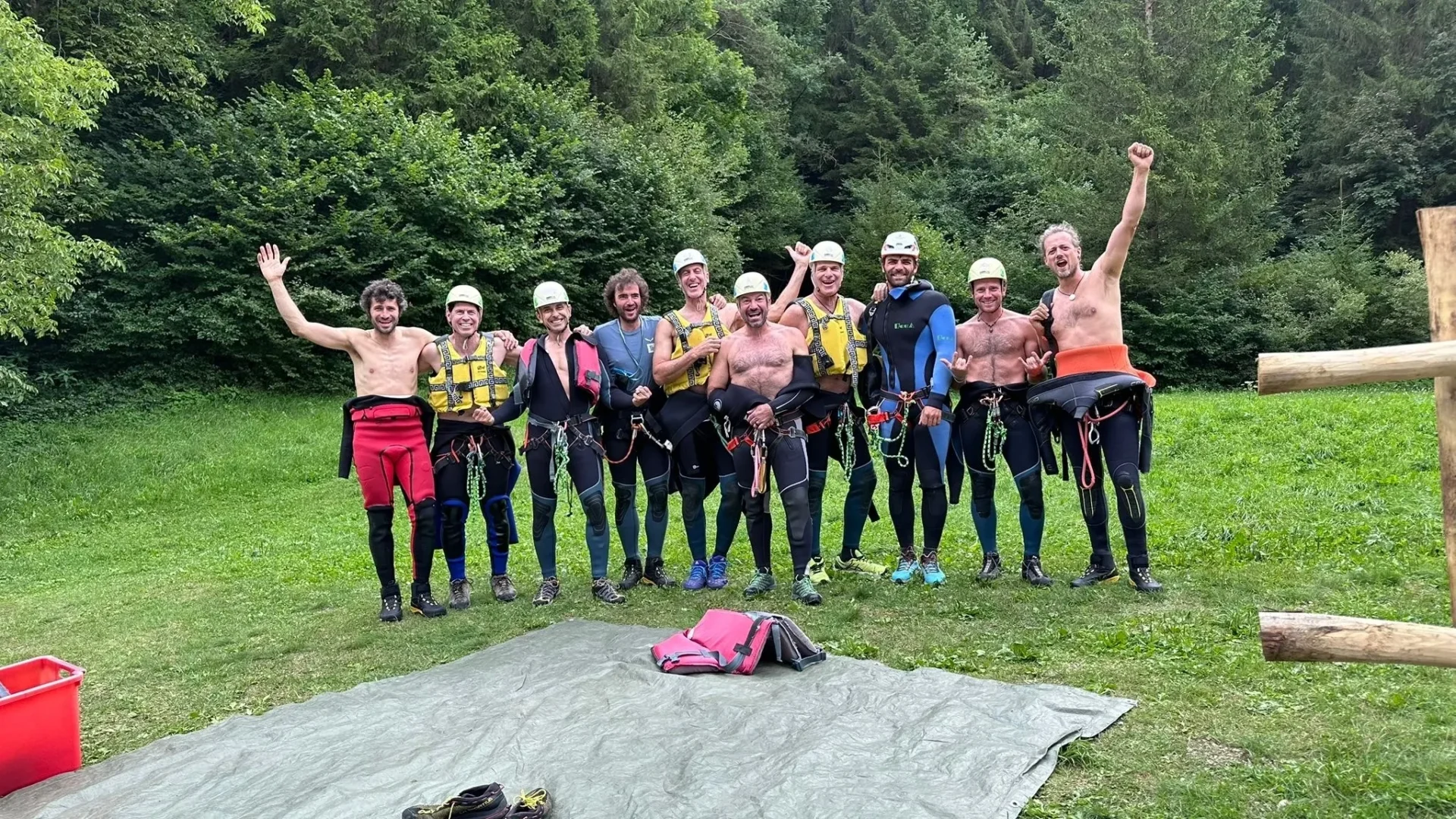 Group of skiers posing on a snowy mountain with lake and peaks behind.