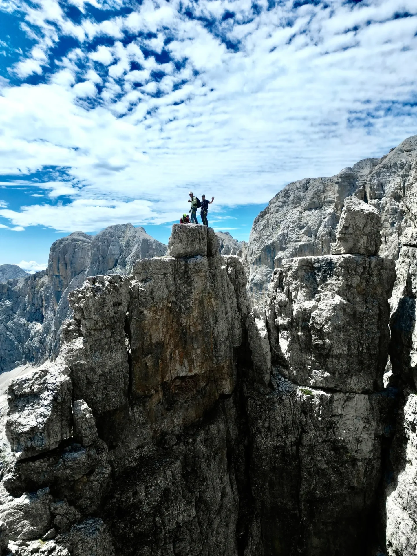 Group of skiers posing on a snowy mountain with lake and peaks behind.
