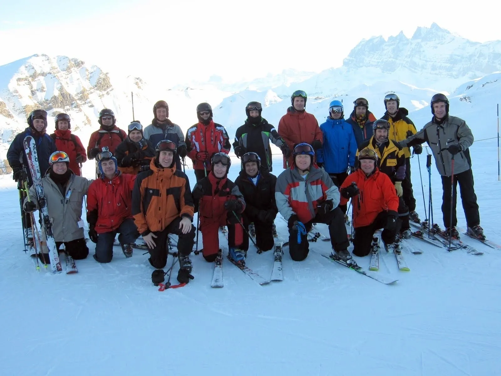 Group of skiers posing on snowy mountain with ski gear.