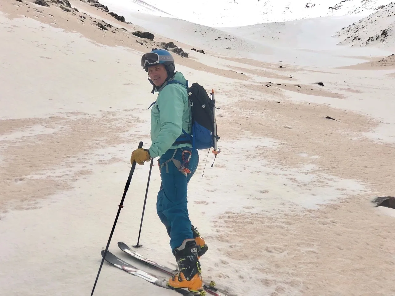 Skier in blue gear on snowy, rocky mountain terrain.