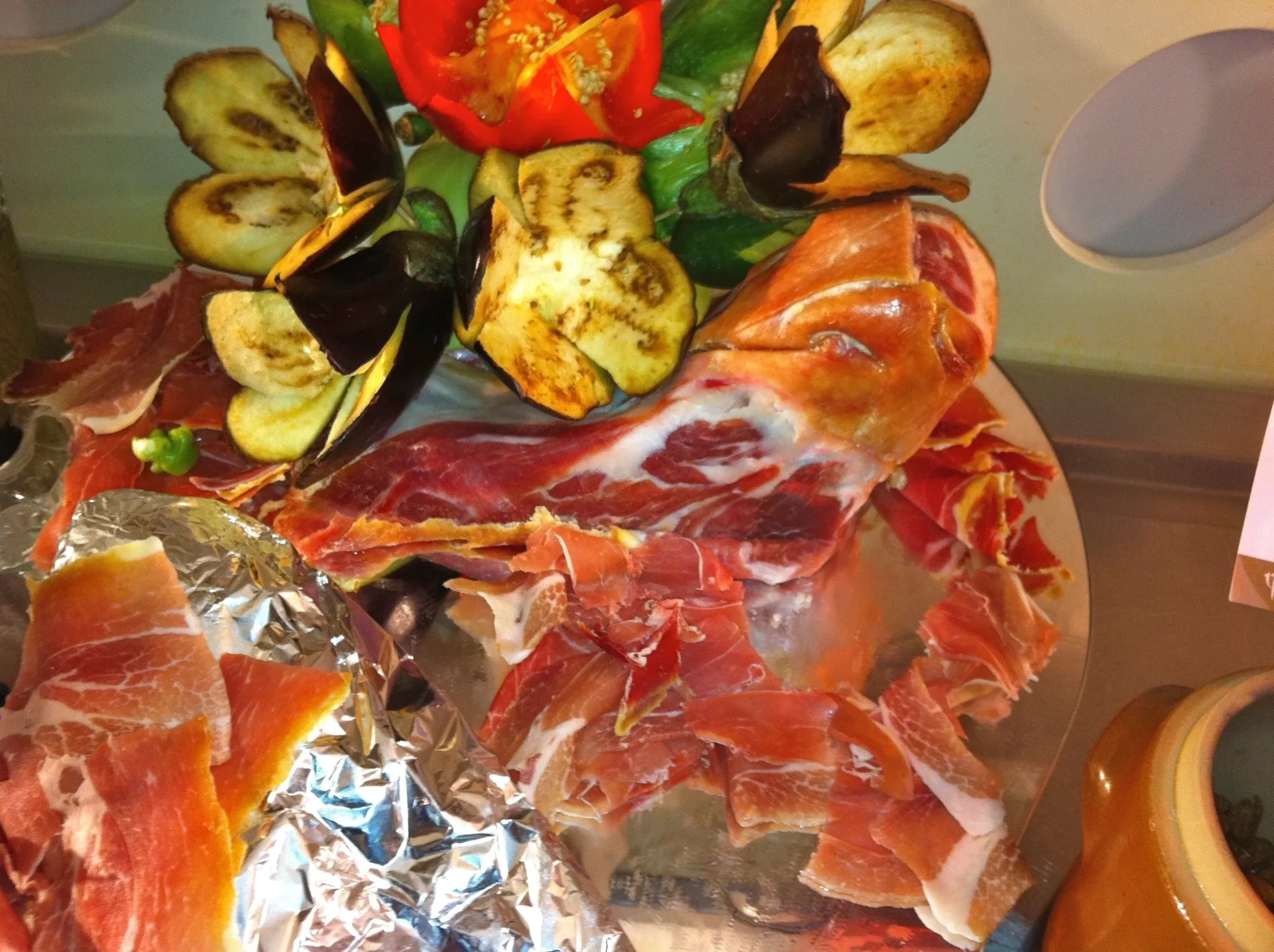 Group of skiers posing on a snowy mountain with lake and peaks behind.