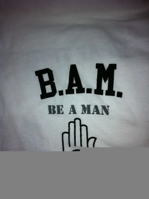 Group of skiers posing on a snowy mountain with lake and peaks behind.