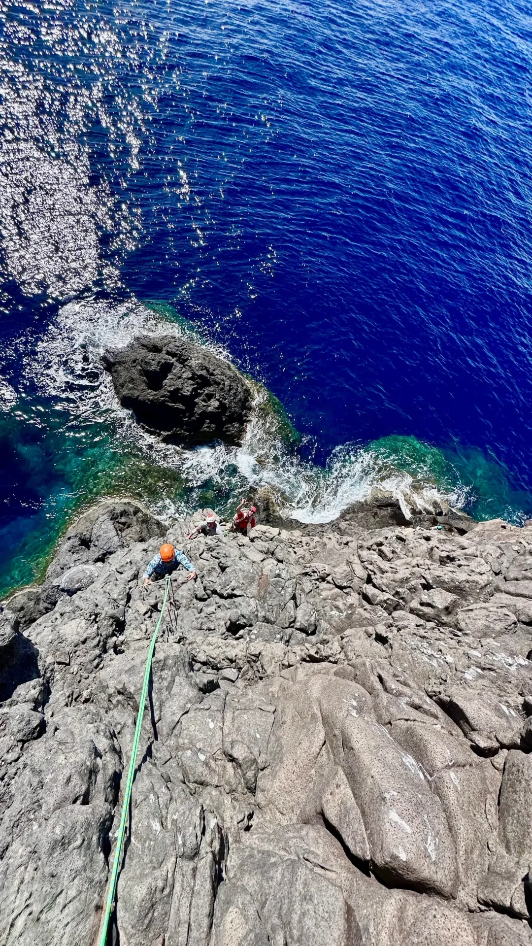 Group of skiers posing on a snowy mountain with lake and peaks behind.