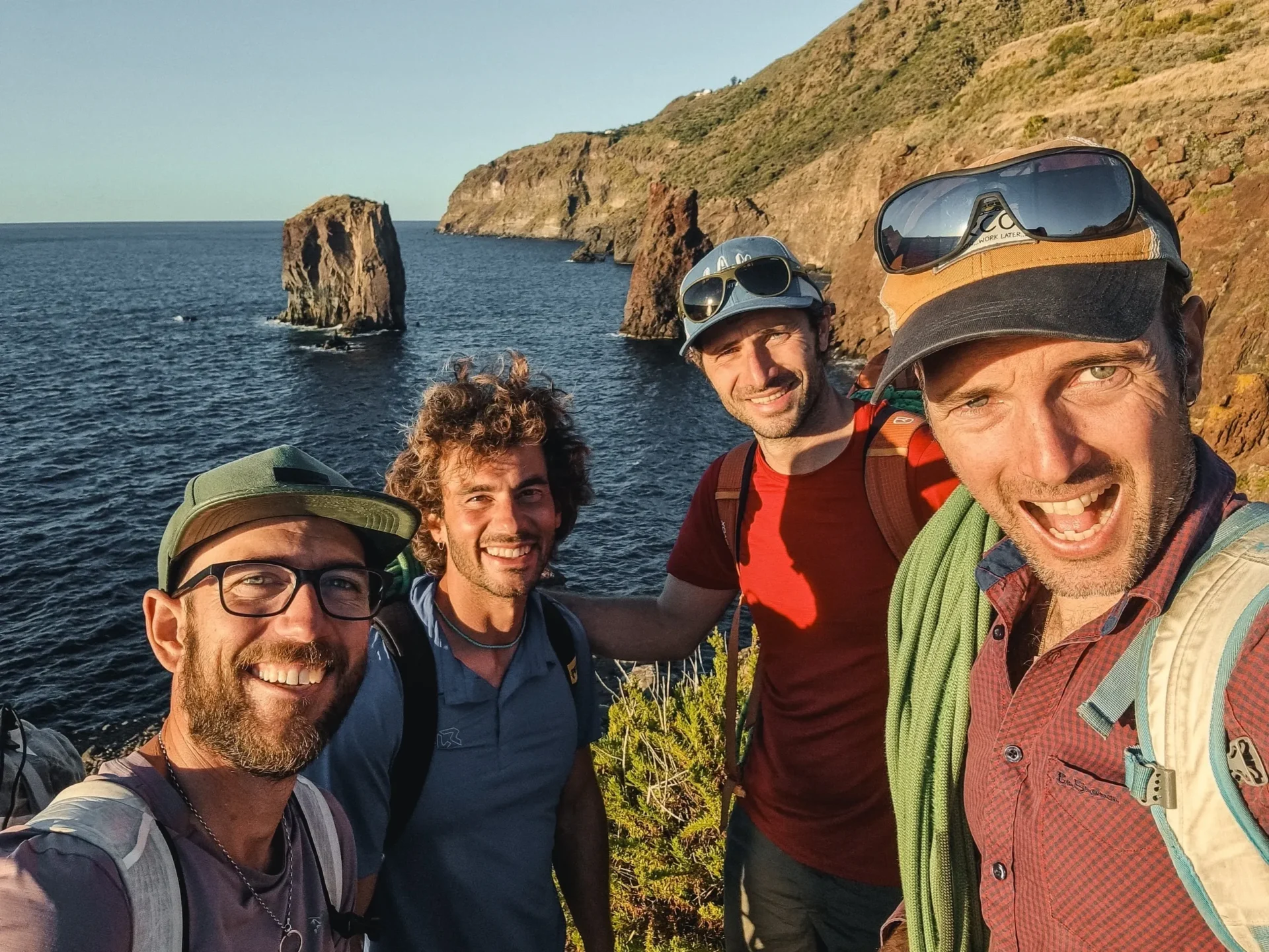Group of skiers posing on a snowy mountain with lake and peaks behind.
