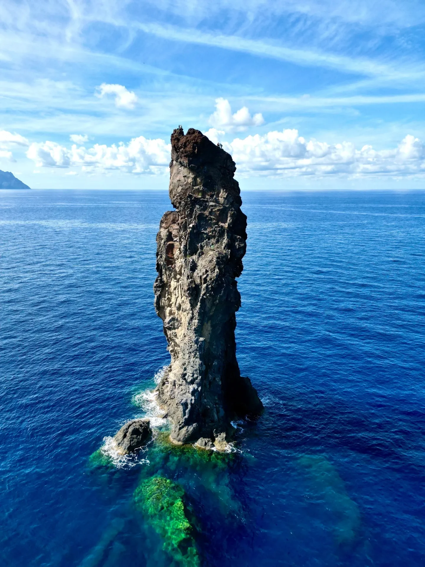 Group of skiers posing on a snowy mountain with lake and peaks behind.