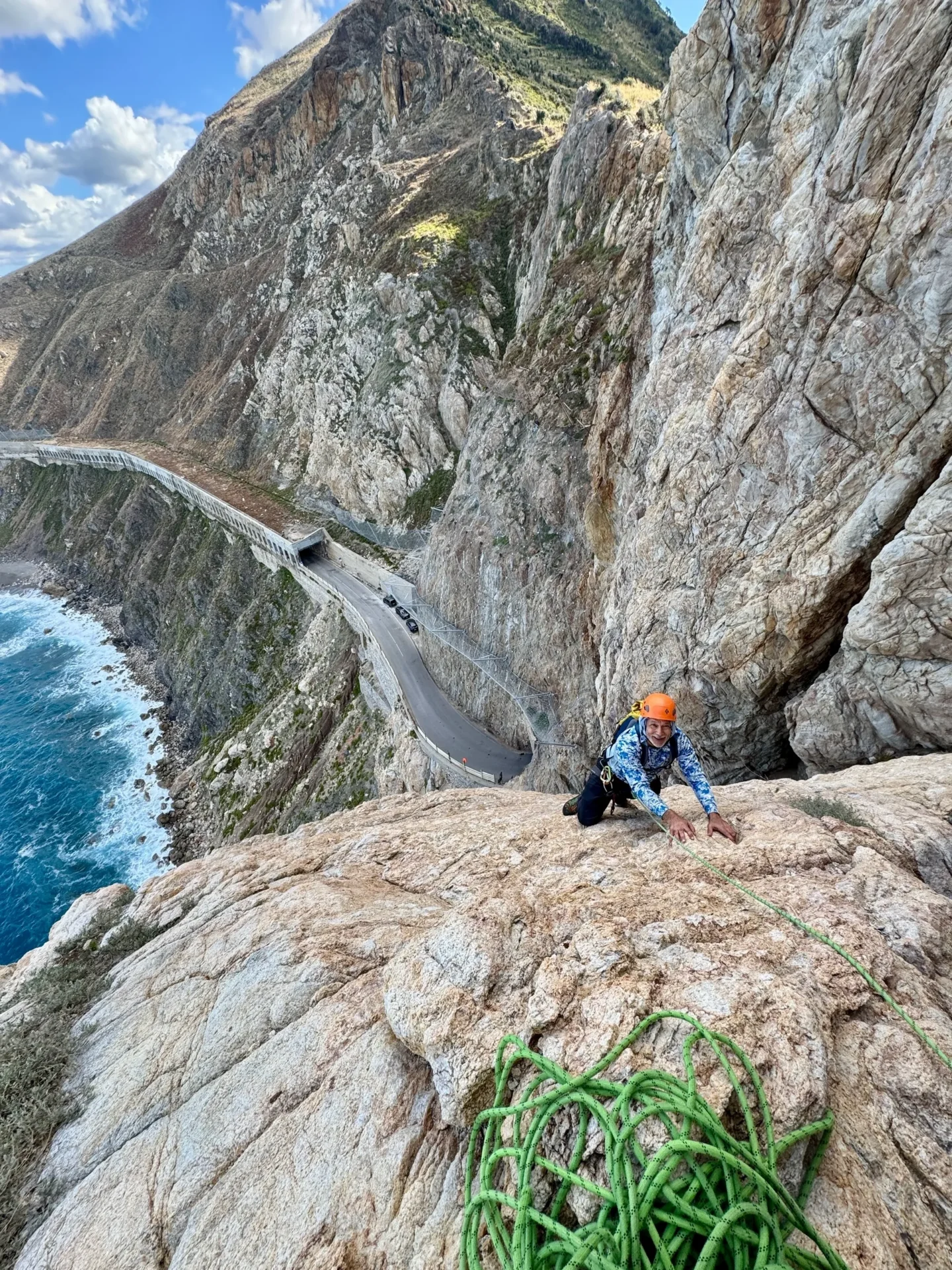 Group of skiers posing on a snowy mountain with lake and peaks behind.