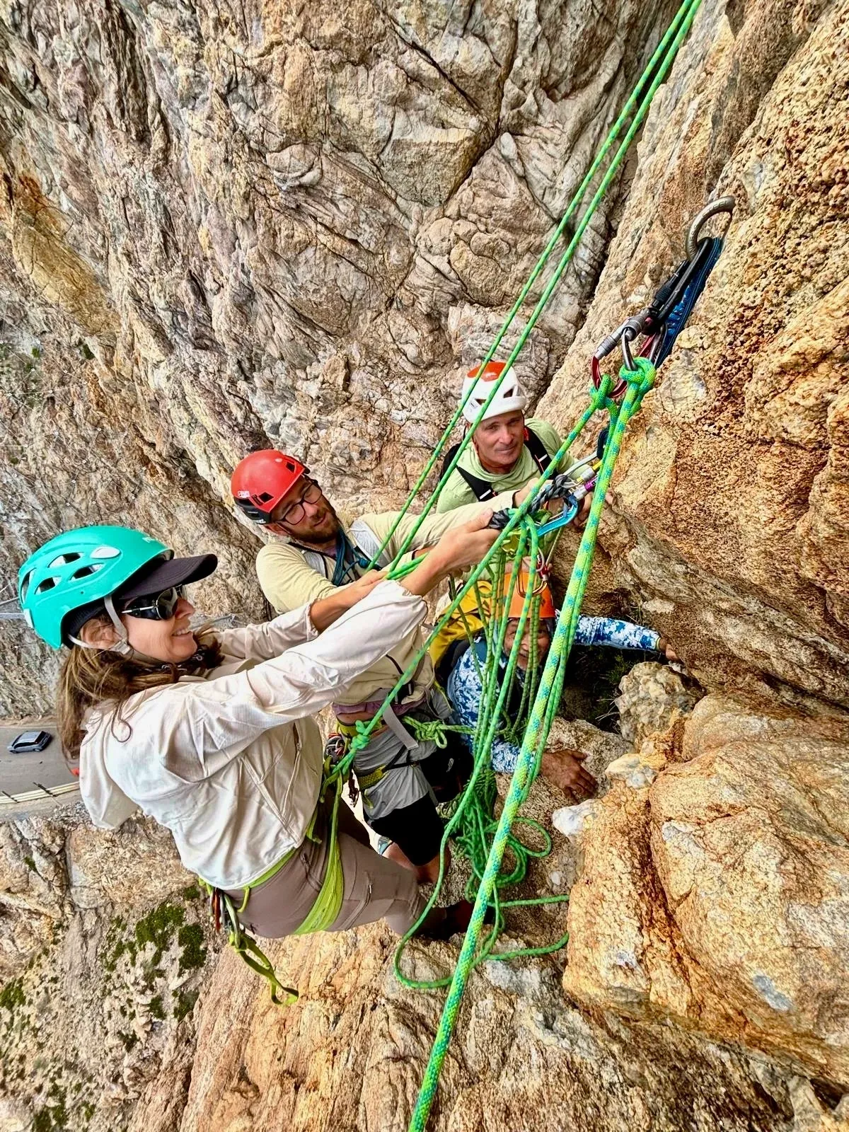 Group of skiers posing on a snowy mountain with lake and peaks behind.
